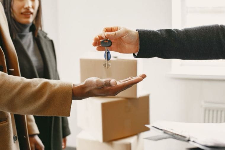 A renter packing moving boxes while holding keys, preparing to break a lease early