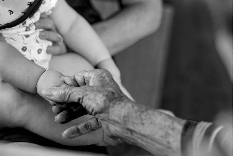 An adult child holding hands with an elderly parent