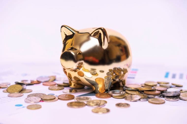 A golden piggy bank surrounded by coins on financial charts