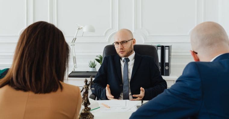 A couple reviewing financial documents with a lawyer across a desk